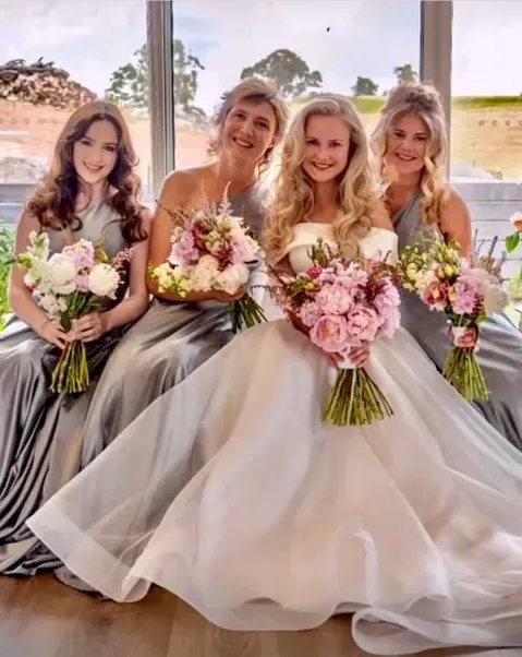 A bride and three bridesmaids holding bouquets, all with soft, loose bridal hair