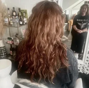 Before: long, one-length brown hair with loose natural waves, seen from behind