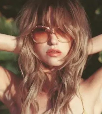 Honey-brown shag with a heavy fringe, styled with tinted 70s sunglasses