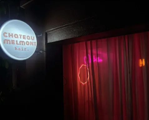 A round illuminated studio sign in front of a red velvet curtain