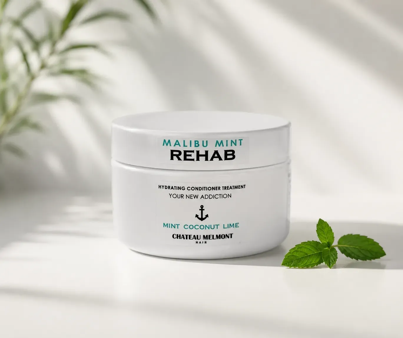A white jar of Malibu Mint Rehab conditioner beside fresh mint leaves