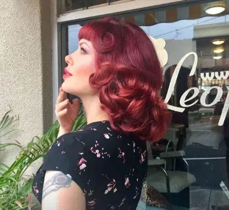 Side profile of glossy red vintage waves set into soft sculpted curls